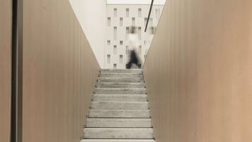 Una escalera moderna con un diseño minimalista que lleva a un edificio de fachada geométrica.