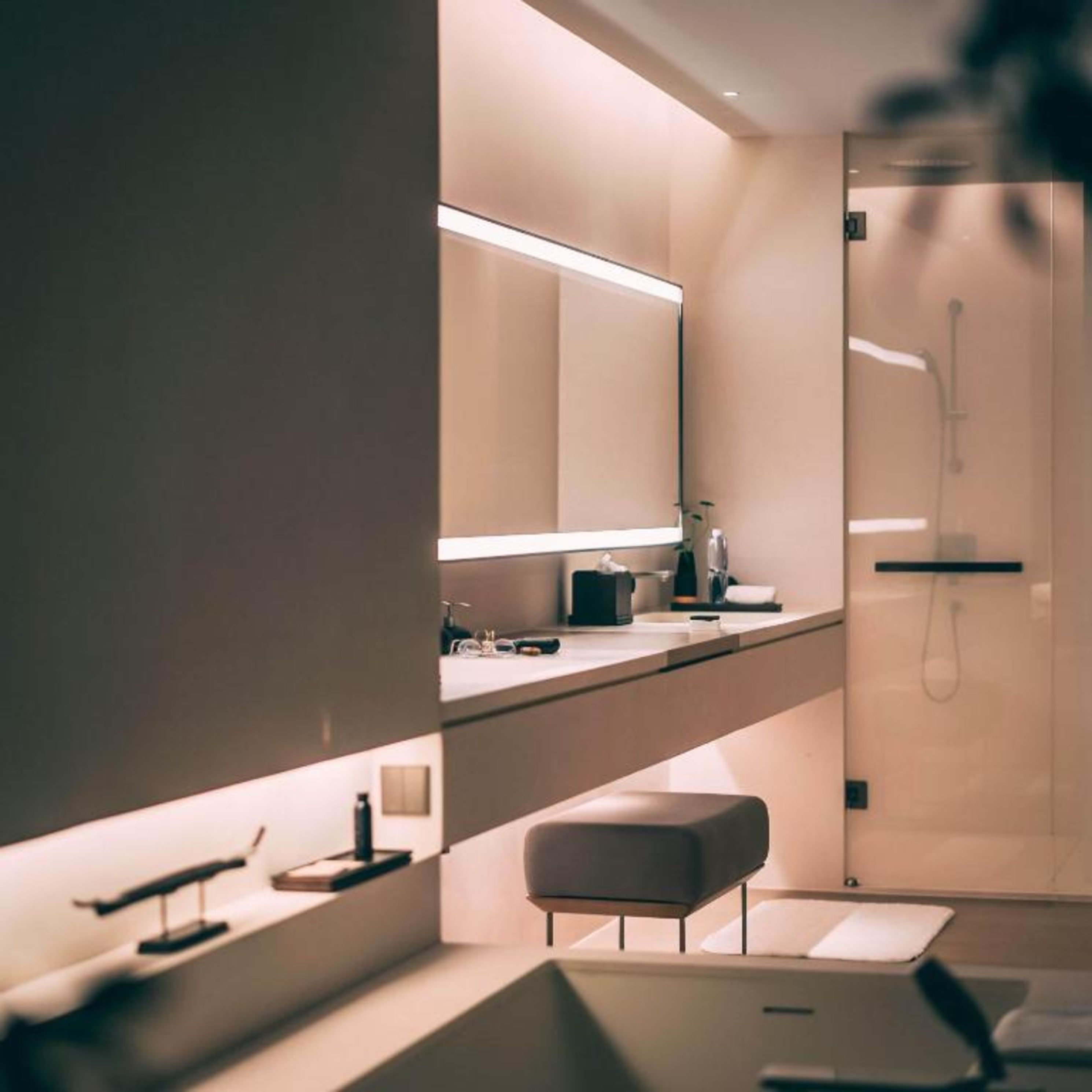 A modern bathroom with a glass shower enclosure, a vanity with a mirror, and a bench.