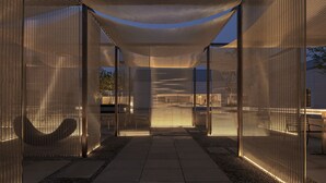 A modern outdoor area with a pathway leading to a seating area, enclosed by transparent mesh walls and illuminated by ambient lighting. - Alila Wuzhen, Zhejiang (Jiaxing)