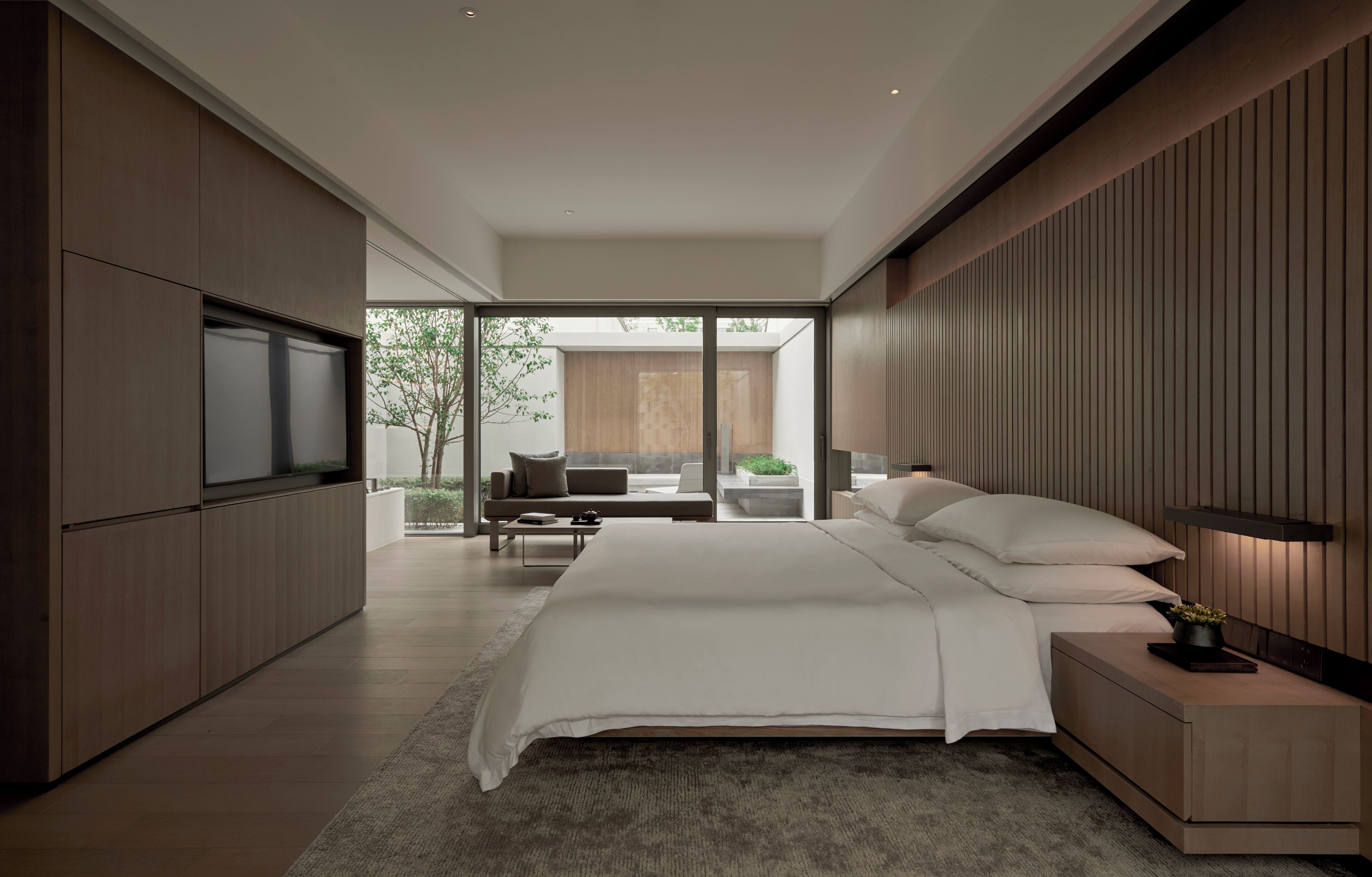 Un dormitorio moderno con una cama grande, televisor y vistas al exterior.