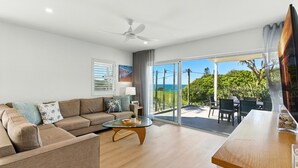 A modern living room with a sofa, coffee table, and a balcony with outdoor furniture.