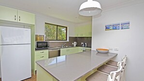 Uma cozinha moderna com uma ilha grande, eletrodomésticos brancos e armários verde-claros.