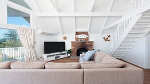 Ein Wohnzimmer mit Fernseher, Sofa und Kamin.