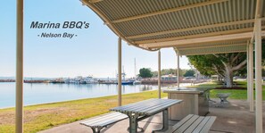 A marina with a covered seating area, a picnic table, and a bench. - Matador Flat - Pet Friendly Accommodation - Close to CBD (NELSON BAY)