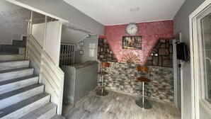 A staircase leading to a landing with a stone wall and a clock above it. - Ersoy Ak Pansiyon (Antalya)