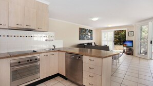 A modern kitchen with a central island, built-in oven, and dishwasher. - Unit 3 'On the Park' at Coolum Beach (Coolum Beach)