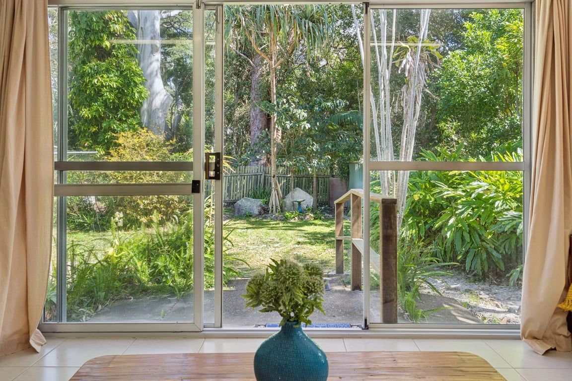 A room with a large sliding glass door leading to a garden.