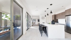 Une cuisine moderne dotée d’un îlot central, de tabourets de bar et d’un réfrigérateur en acier inoxydable.