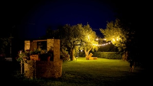A nighttime outdoor setting with a stone structure, string lights, and a well-maintained lawn. - Zà Culetta (Rocca San Giovanni)