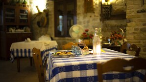 A dining area with a checkered tablecloth, wooden chairs, a bottle of water, and a vase with flowers. - Zà Culetta (Rocca San Giovanni)