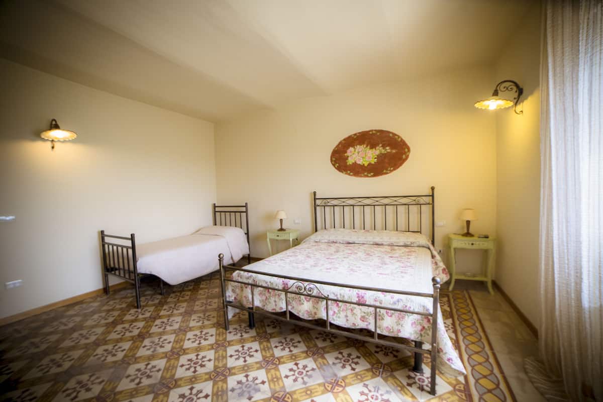 A bedroom with a single bed, two bedside tables, and a decorative wall hanging.