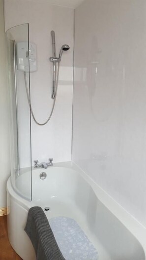 Ein Badezimmer mit einer weißen Badewanne, einer Duschbrause und einem Handtuchhalter.