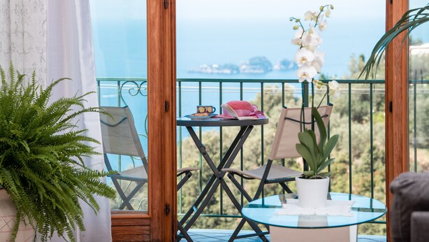 A balcony with a table, chairs, and a potted plant. - Positano Villa Genny and Emily breakfast & experience (Positano,Montepertuso)