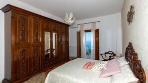 A bedroom with a large bed, a wardrobe, and a view of the sea through a balcony. - Positano Villa Genny and Emily breakfast & experience (Positano,Montepertuso)