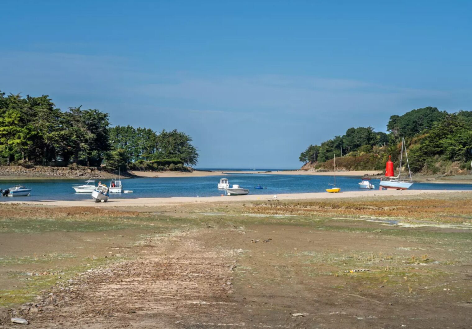 Ein Strand mit Booten und einem Sandweg zum Wasser.