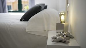 A neatly made bed with white linens, a bedside table with a small lamp, and a decorative object resembling a snowflake. - Luxury Villa in Maspalomas, Jacuzzi, Wifi, Pool, Parking (Maspalomas)