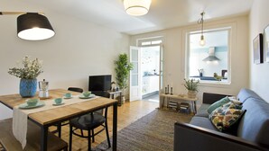 A modern living room with a wooden dining table, a sofa, and a TV. - Family Matters | Historic Center (Porto)