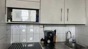 Keittiössä on mikroaaltouuni, leivänpaahdin, pesuallas ja teline, jossa on ruokailuvälineitä.