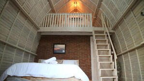 Dormitorio estilo loft con escalera de madera, cama y pared de ladrillo.
