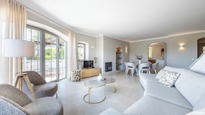 A modern living room with a sofa, armchairs, a coffee table, and a TV.