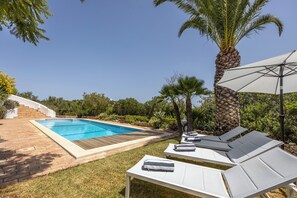 Een buitenzwembad, een verwarmd zwembad, ligstoelen bij het zwembad