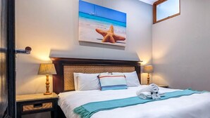 A hotel room with a large bed, two bedside lamps, a starfish artwork on the wall, and a window with a view of the sea. - Ballito Bay holiday Apartment (Ballito)