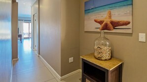 A hallway with a starfish decoration on a wall and a glass jar with seashells on a console table. - Ballito Bay holiday Apartment (Ballito)