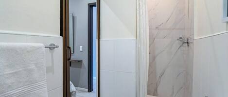 A bathroom with a shower, a toilet, and a mirror.