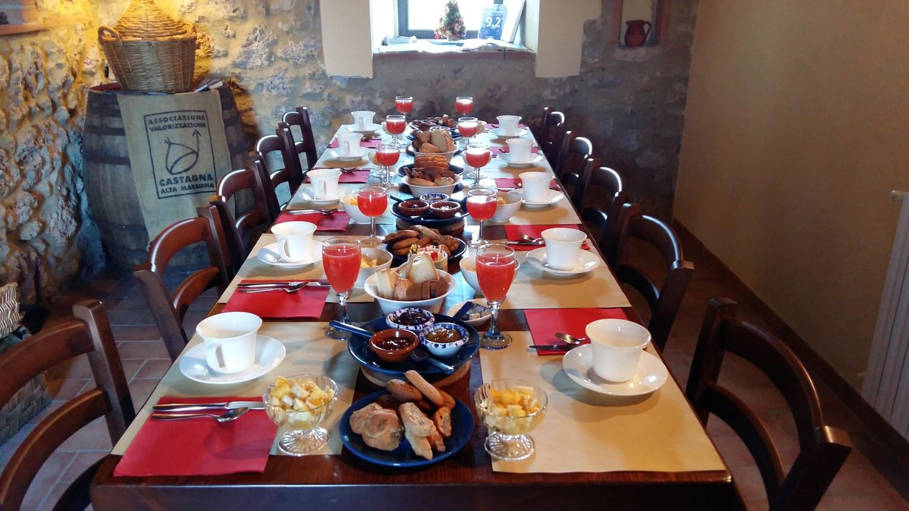 A long dining table set with various breakfast items, including bread, pastries, and fruit.