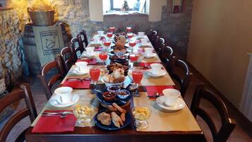 A long dining table set with various breakfast items, including bread, pastries, and fruit.