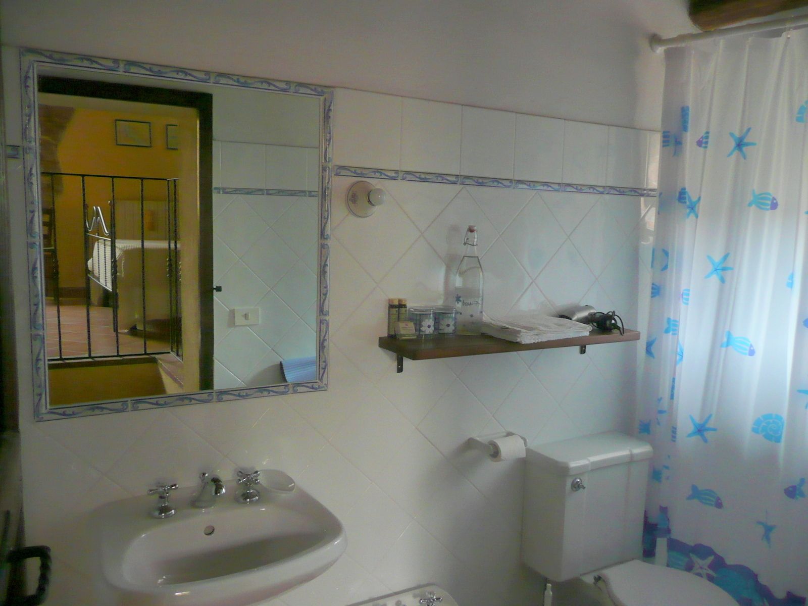 A bathroom with a sink, mirror, toilet, and shower curtain.