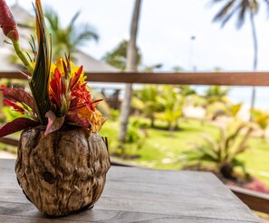 Una jardinera de madera rústica con flores tropicales en un balcón con vistas a un jardín ajardinado.