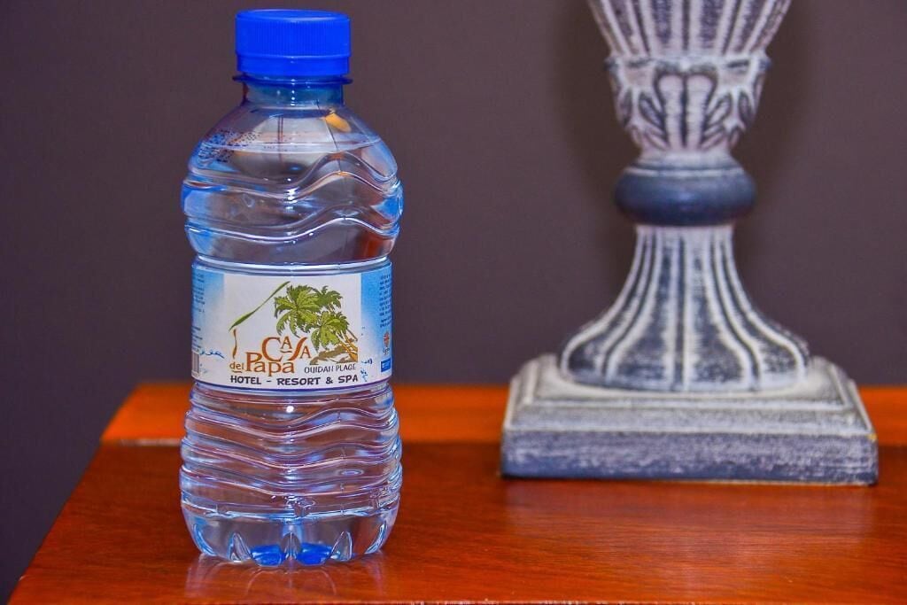 A water bottle with a label on a wooden surface next to a decorative pillar.