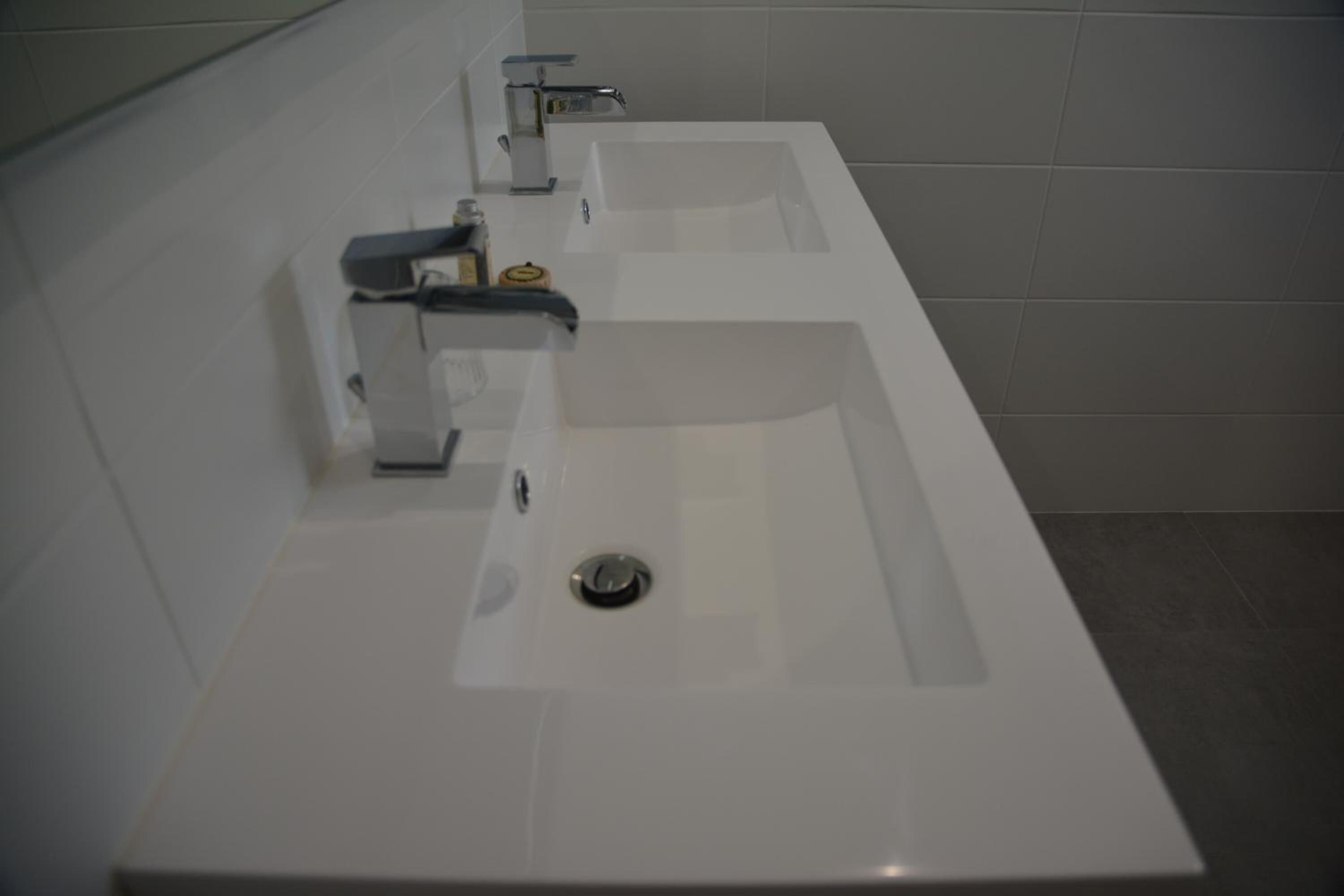 A modern bathroom with three sinks, each equipped with a faucet and a soap dispenser.