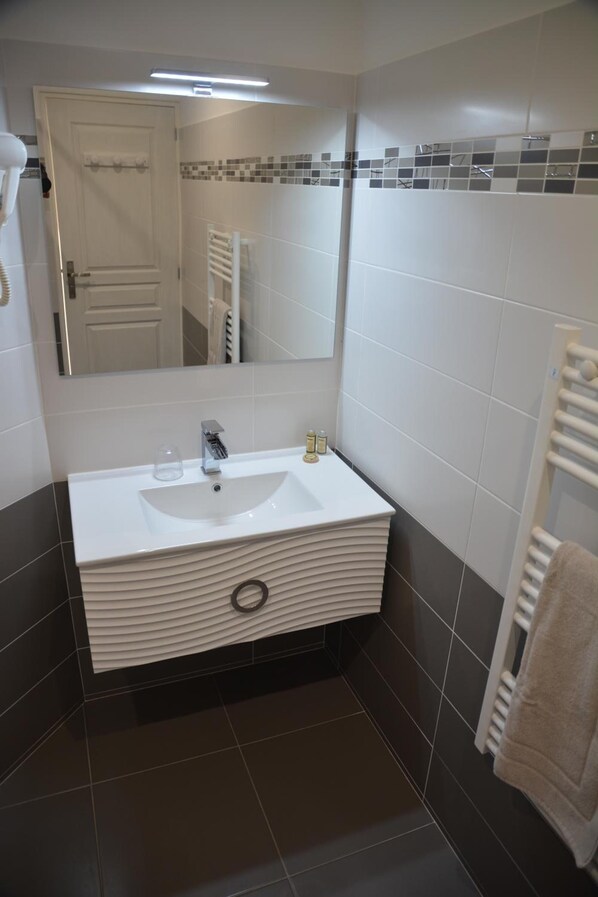 A modern bathroom with a white sink, mirror, and towel rack.