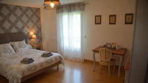 Una camera da letto con un letto, comodino, sedia, scrivania e tende.