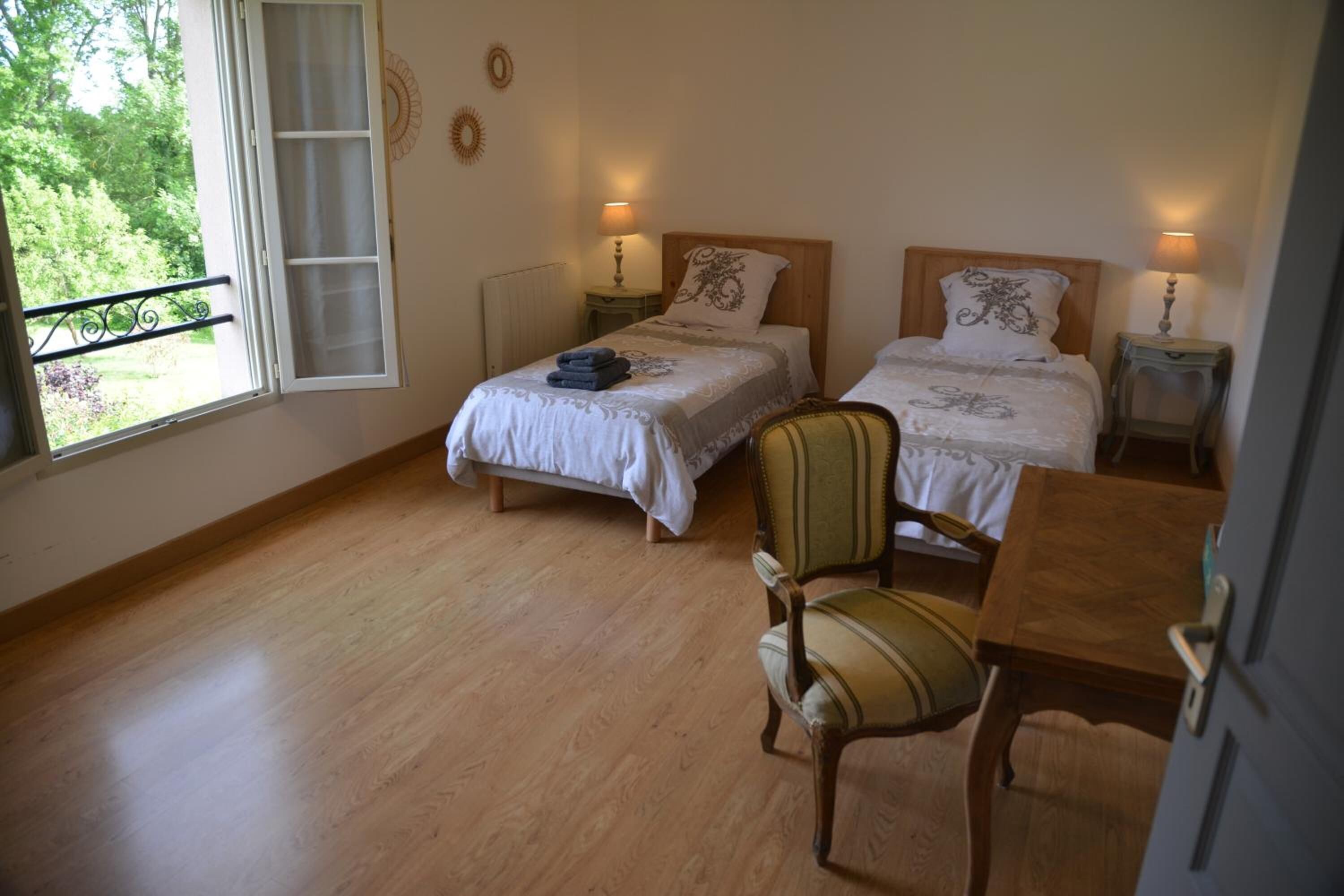 Une chambre avec deux lits, un plancher en bois, une chaise et une table.