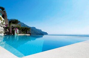 A clear blue pool with a view of a mountain and the sea.