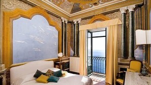 Ein luxuriöses Hotelzimmer mit einem großen Bett, einem Esstisch und einem Balkon mit Blick.