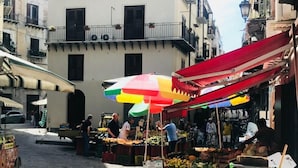 A street market with vendors selling fruits and vegetables under colorful umbrellas. - Reginella B&B Palermo (Palermo)