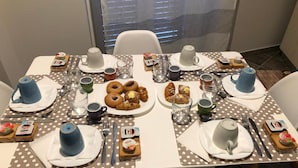 A dining table set with various breakfast items, including pastries, a plate of donuts, and cups. - Reginella B&B Palermo (Palermo)