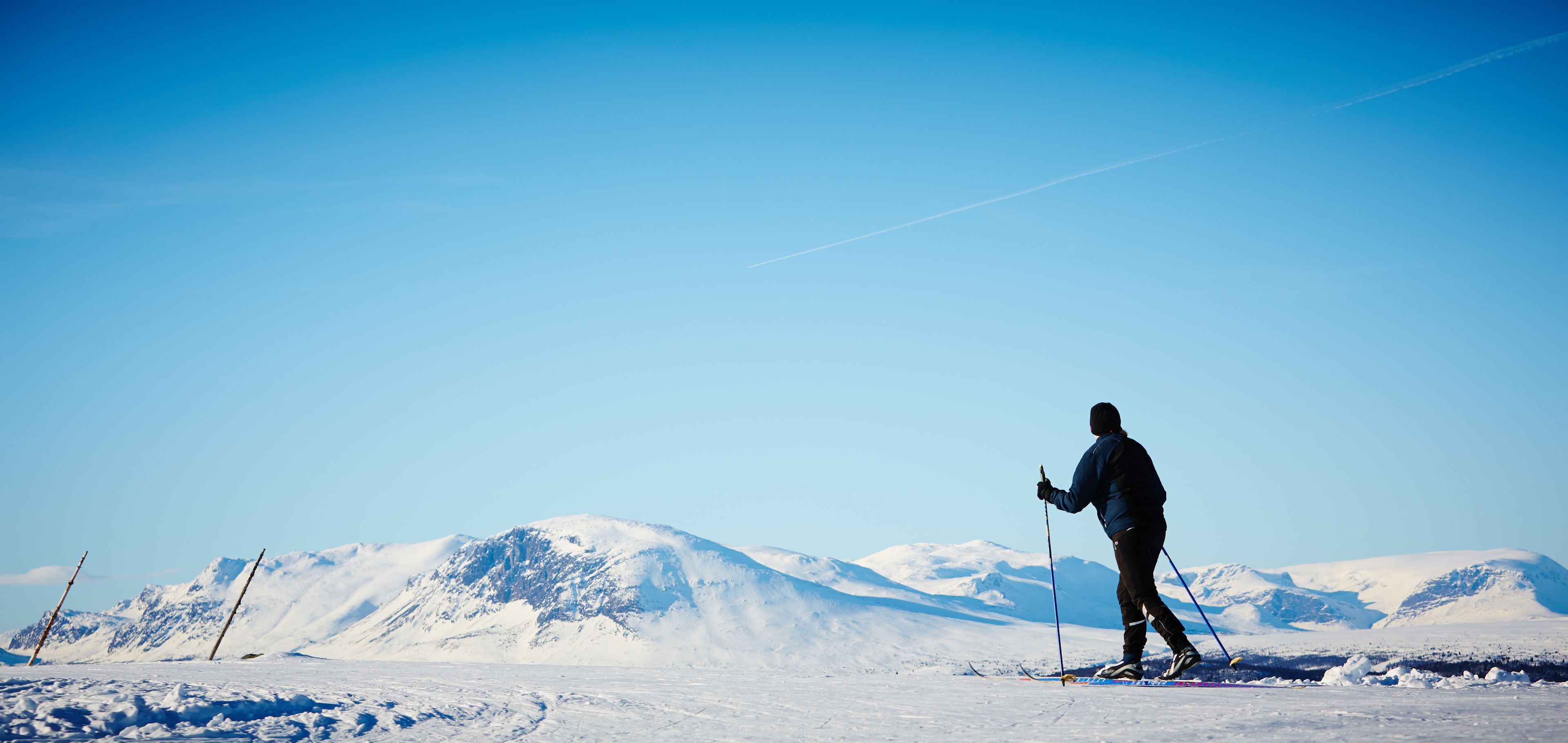 Una persona esquiando en una montaña nevada bajo cielos despejados.
