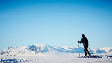 Una persona esquiando en una montaña nevada bajo cielos despejados.
