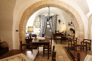 Un comedor con un arco de piedra, muebles de madera y una araña.