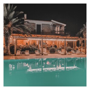 A poolside area with lounge chairs and a pool, surrounded by a building with a stone facade and a covered patio area. - Le Cese (San Giovanni Rotondo)