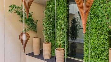 A modern interior with hanging light fixtures, green vertical gardens, and potted plants on shelves.