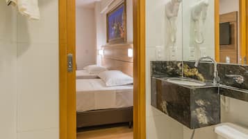 Un baño de hotel con cama, lavamanos e inodoro.