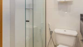 Un baño moderno con ducha de vidrio, inodoro blanco y toallero con toallas.