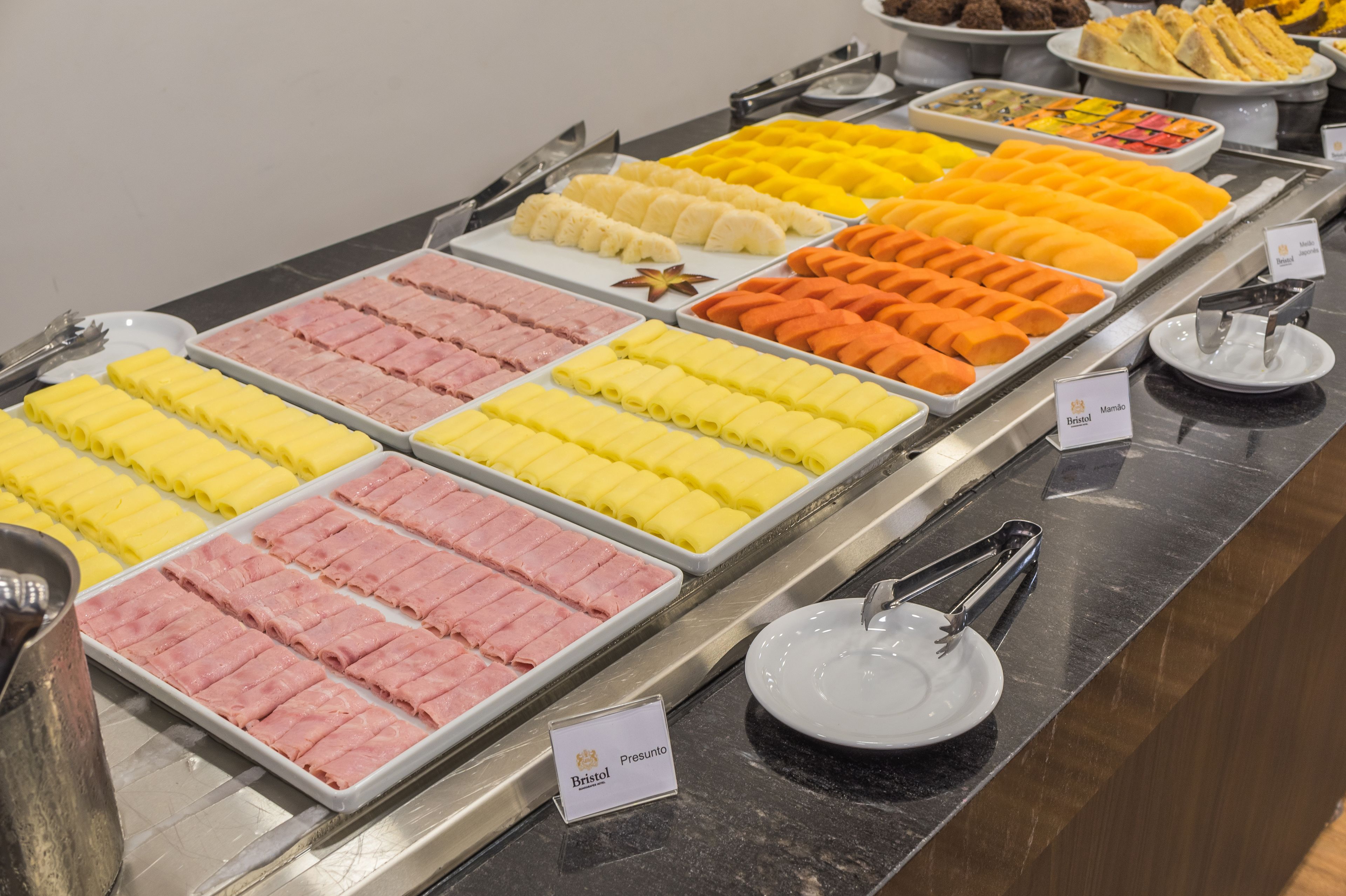 A buffet with various food items arranged in trays, including different types of pastries and desserts.