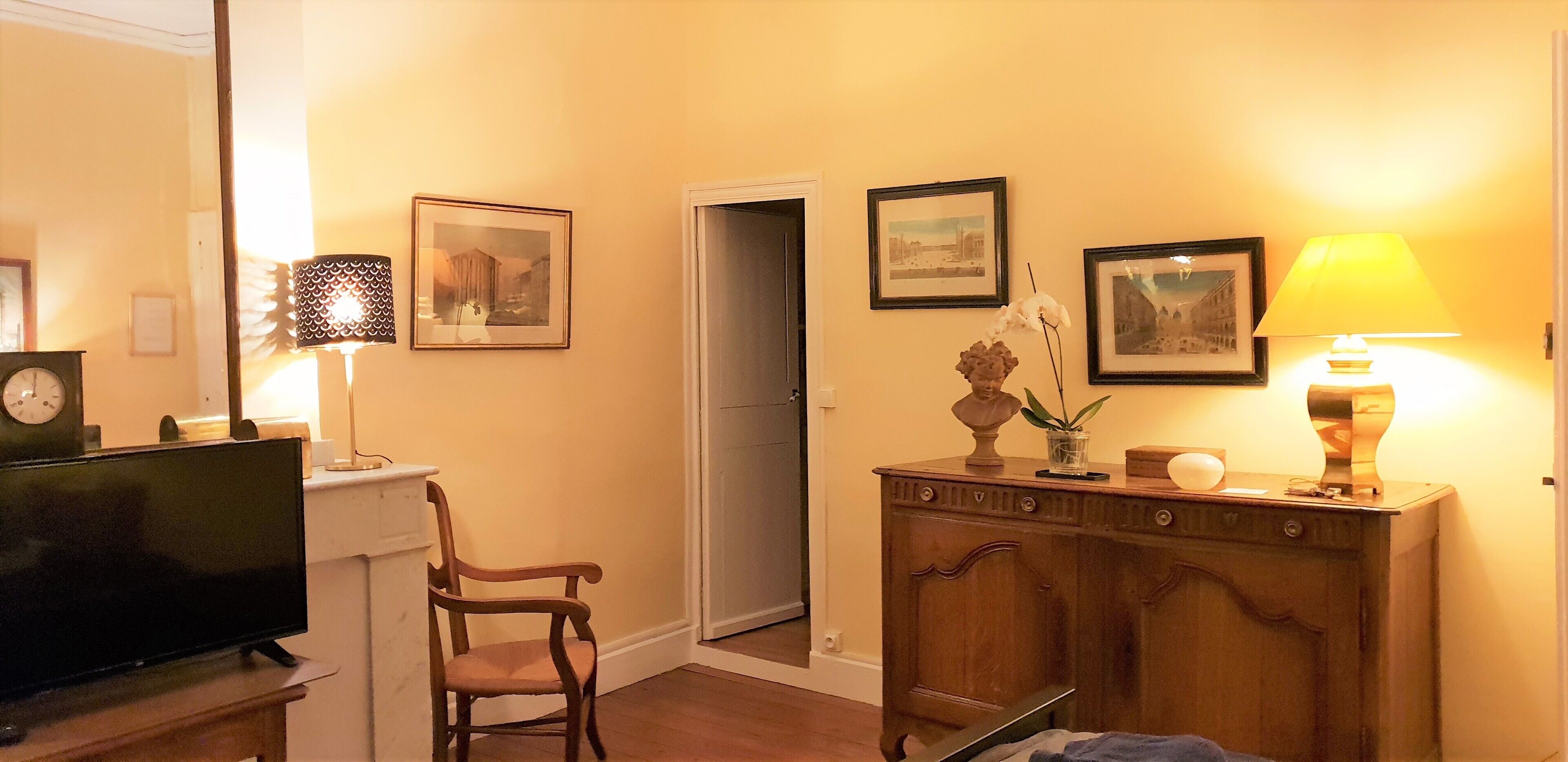 Une pièce avec un meuble en bois, une télévision, une chaise et des tableaux encadrés accrochés au mur.